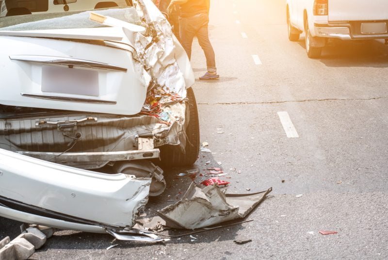 A silver car is wrecked on the side of the road
