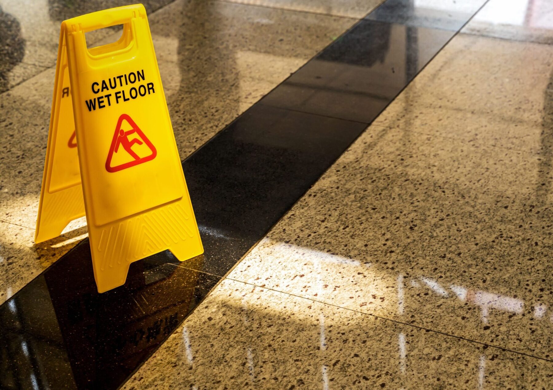 Yellow "Caution: Wet Floor" sign on a marble floor.