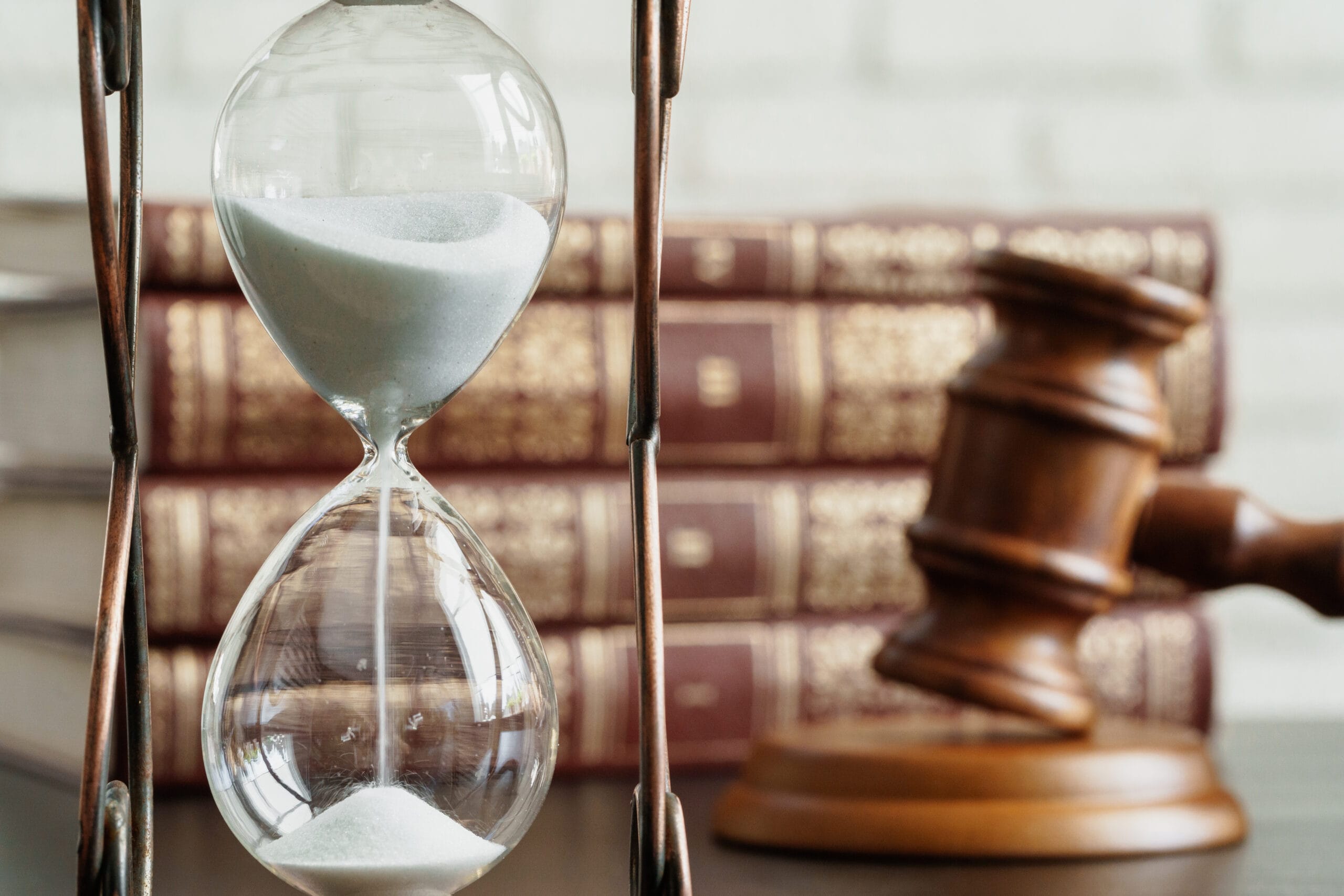 An hourglass placed next to a gavel and legal books.