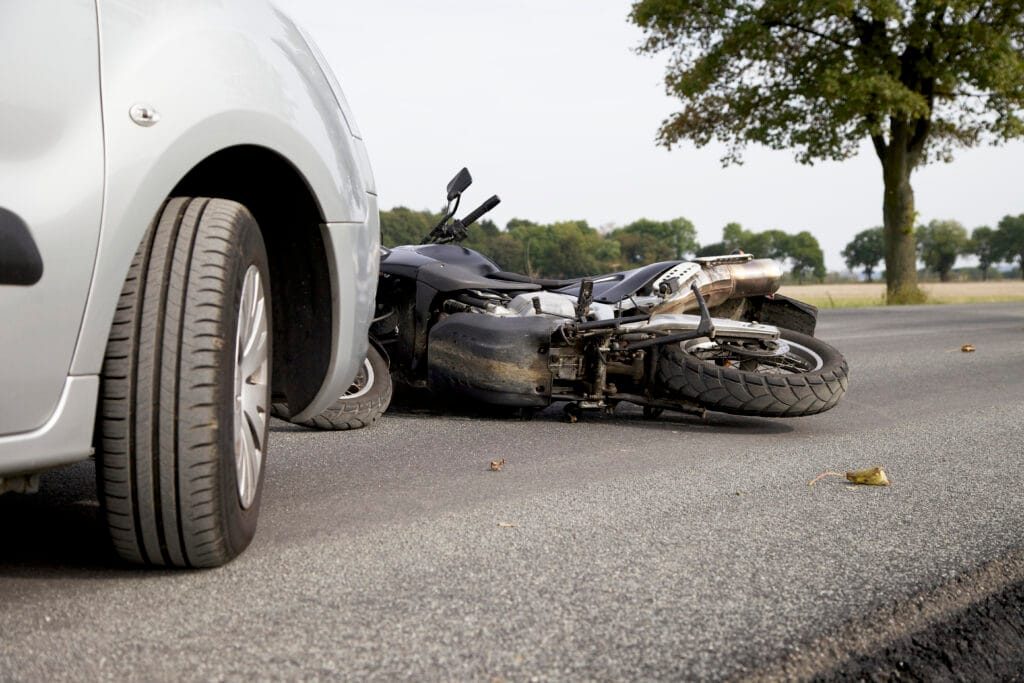 Close-up of a motorcycle lying on the road after a collision with a car.